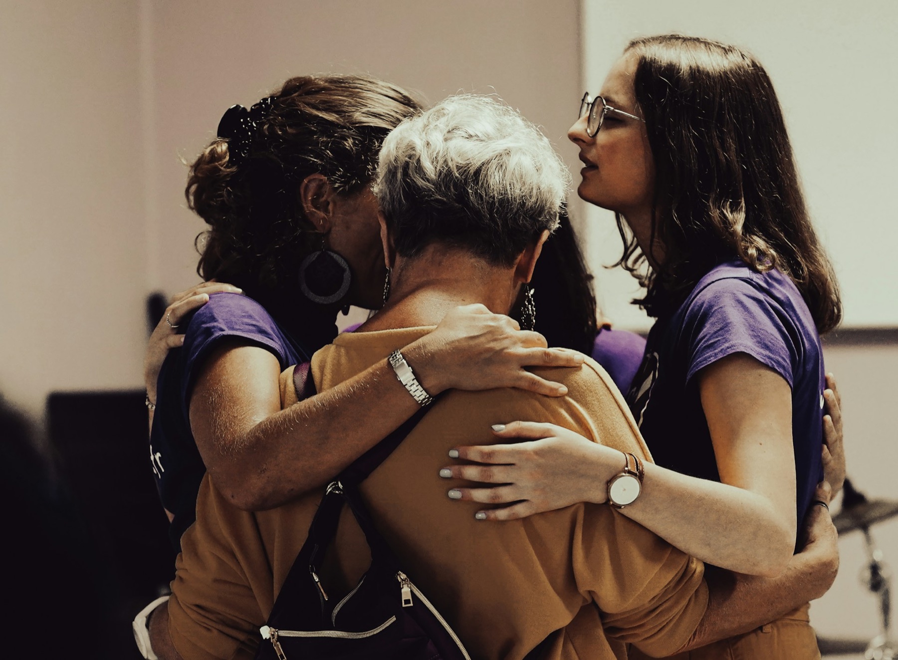 Plusieurs femmes se tiennent par les épaules, dans un geste de soutien.